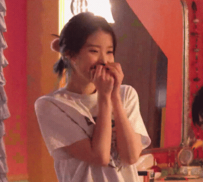 A Woman Covering Her Mouth With Her Hands In Front Of A Mirror GIF