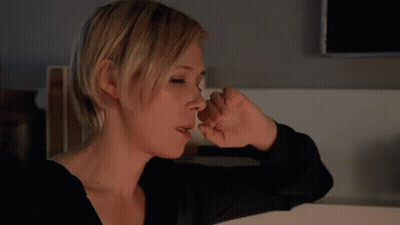 A Woman Covering Her Nose With Her Hand While Looking Down GIF