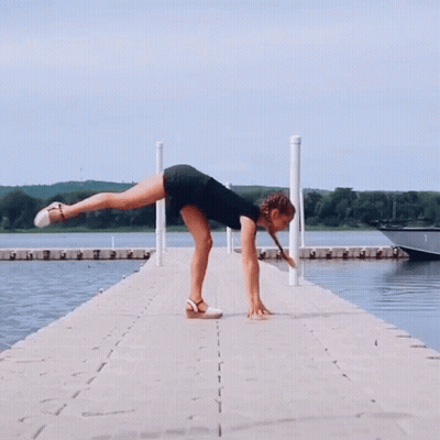 A Woman Doing A Split On A Dock Next To A Boat GIF