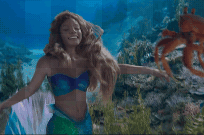 A Woman Dressed As A Mermaid Is Holding A Crab In Her Hands GIF