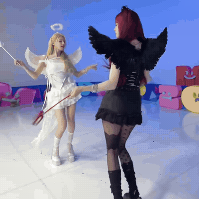 A Woman Dressed As An Angel And A Woman Dressed As A Devil Are Standing Next To Each Other GIF