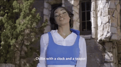 A Woman Dressed As Belle From Beauty And The Beast Is Standing In Front Of A Stone Building With Her Eyes Closed . GIF
