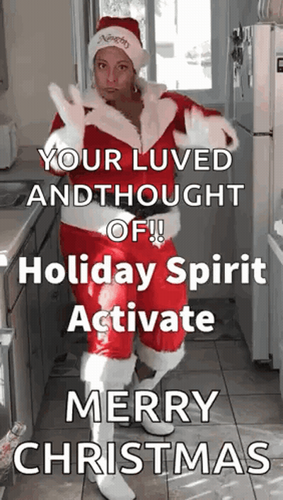 A Woman Dressed As Santa Claus Is Standing In A Kitchen With A Christmas Message GIF