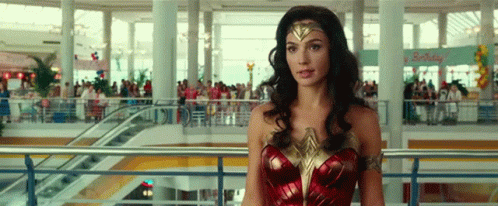 A Woman Dressed As Wonder Woman Is Standing In A Mall . GIF