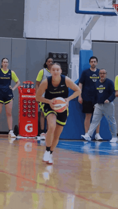 A Woman Dribbles A Basketball In Front Of A Gatorade Cooler GIF