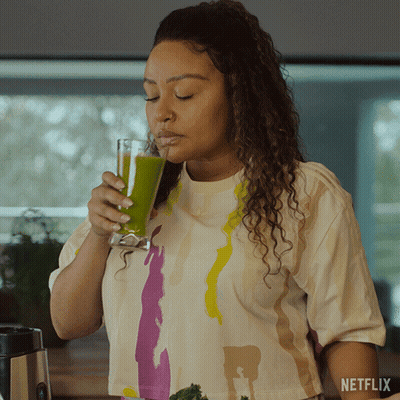 A Woman Drinking A Green Smoothie With A Netflix Logo On The Bottom GIF