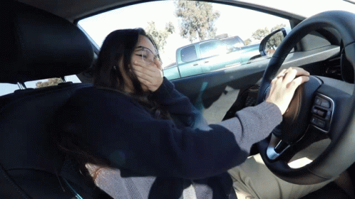 A Woman Driving A Car With Her Hand Over Her Mouth GIF