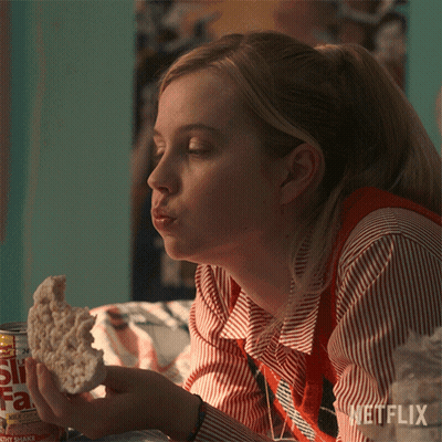 A Woman Eating A Piece Of Bread Next To A Can Of Soda That Says St. Fa GIF