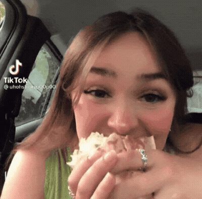 A Woman Eating A Sandwich In A Car With A Tiktok Watermark On The Bottom Right GIF