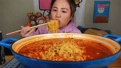 A Woman Eating Ramen With Chopsticks From A Pot GIF