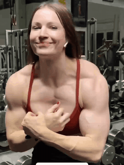 A Woman Flexes Her Muscles In A Gym GIF