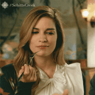 A Woman From Schitts Creek Is Eating With A Fork And Spoon GIF