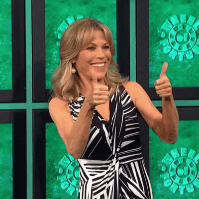 A Woman Giving A Thumbs Up In Front Of A Green Wall GIF