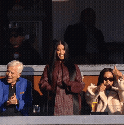 A Woman Giving A Thumbs Up In Front Of A Man In A Blue Jacket GIF