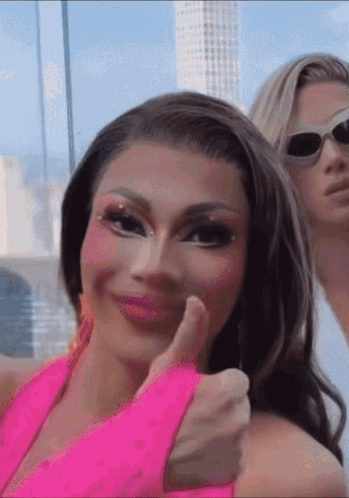 A Woman Giving A Thumbs Up Next To Another Woman Wearing Sunglasses GIF