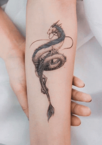 A Woman Has A Tattoo Of A Dragon On Her Forearm GIF