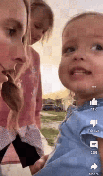 A Woman Holding A Baby With A Thumbs Up And Dislike Buttons On The Bottom GIF