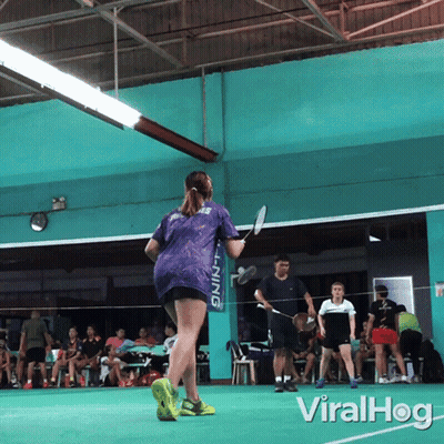A Woman Holding A Badminton Racket In Front Of A Li Ning Banner GIF