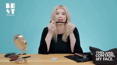 A Woman Holding A Blush Brush In Front Of A Bag That Says " This Bag Contains My Face " GIF