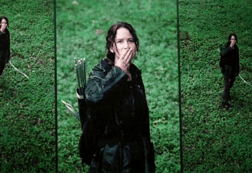 A Woman Holding A Bow And Arrow Covering Her Mouth GIF