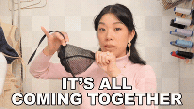 A Woman Holding A Bra With The Words It 'S All Coming Together Behind Her GIF