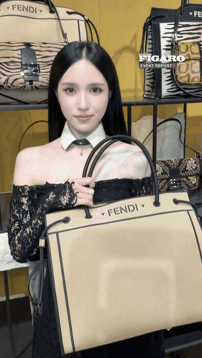 A Woman Holding A Fendi Bag In Front Of A Display Of Bags GIF