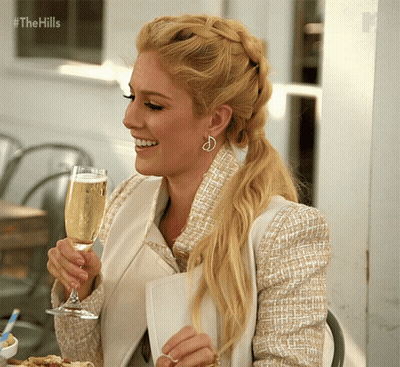 A Woman Holding A Glass Of Champagne With The Hills Written In The Corner GIF