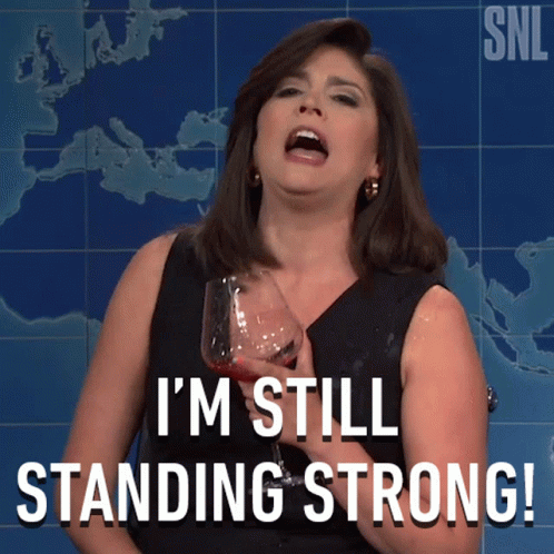 A Woman Holding A Glass Of Wine With The Words I 'M Still Standing Strong GIF