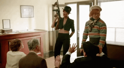 A Woman Holding A Gun Is Surrounded By People GIF