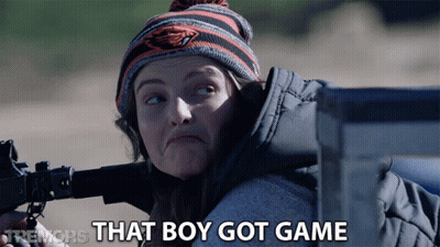 A Woman Holding A Gun With The Words That Boy Got Game Behind Her GIF