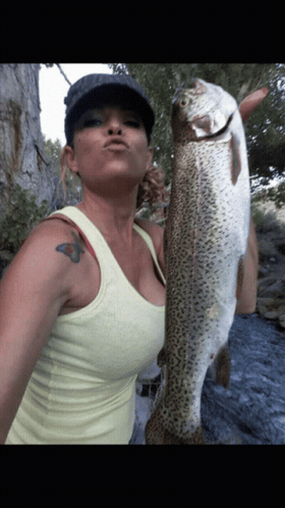 A Woman Holding A Large Fish With A Tattoo On Her Arm GIF