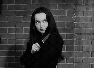 A Woman Holding A Large Knife In Front Of A Brick Wall GIF