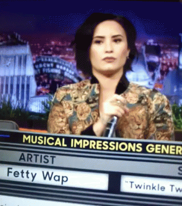 A Woman Holding A Microphone Behind A Sign That Says Musical Impressions Gener GIF