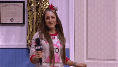 A Woman Holding A Microphone In Front Of A University Of Pittsburgh Certificate GIF