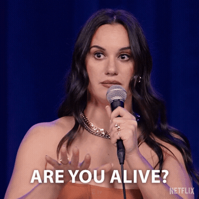 A Woman Holding A Microphone With The Words Are You Alive Behind Her GIF