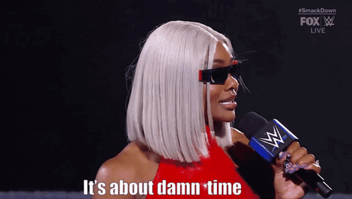 A Woman Holding A Microphone With The Words It 'S About Damn Time Behind Her GIF