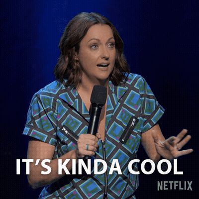 A Woman Holding A Microphone With The Words " It 'S Kinda Cool " Below Her GIF