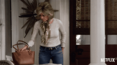 A Woman Holding A Purse In Front Of A Netflix Sign GIF