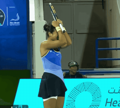 A Woman Holding A Tennis Racket In Front Of An Abu Dhabi Sports Lounge Sign GIF