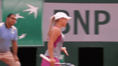 A Woman Holding A Tennis Racquet In Front Of A Bnp Banner GIF