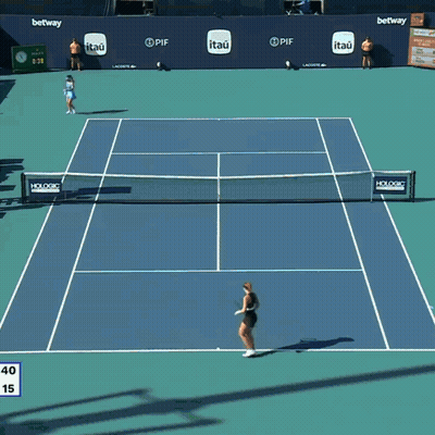 A Woman Holding A Tennis Racquet In Front Of A Lex Clock GIF