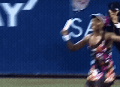 A Woman Holding A Tennis Racquet In Front Of A Sign That Says S. GIF