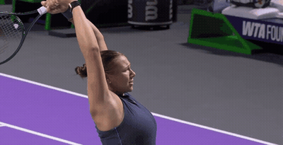 a woman holding a tennis racquet on a purple court