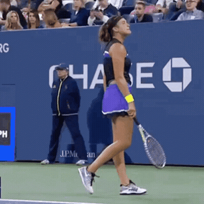 A Woman Holding A Tennis Racquet On A Tennis Court With Chase In The Background GIF