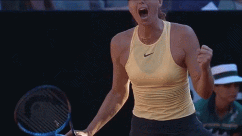 A Woman Holding A Tennis Racquet With Her Mouth Open GIF