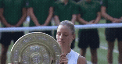 A Woman Holding A Trophy In Front Of A Crowd Of People GIF