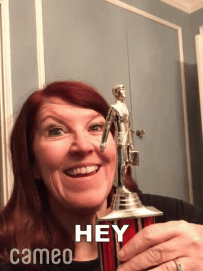 A Woman Holding A Trophy That Says Hey Cameo On The Bottom GIF