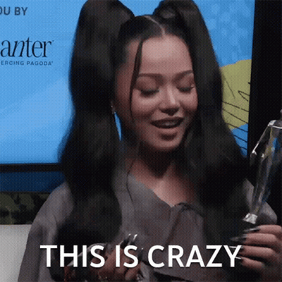 A Woman Holding A Trophy With The Words This Is Crazy Behind Her GIF