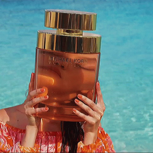 A Woman Holds A Bottle Of Michael Kors Perfume In Front Of Her Face GIF
