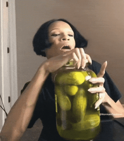 A Woman Holds A Jar Of Pickles In Her Hand GIF
